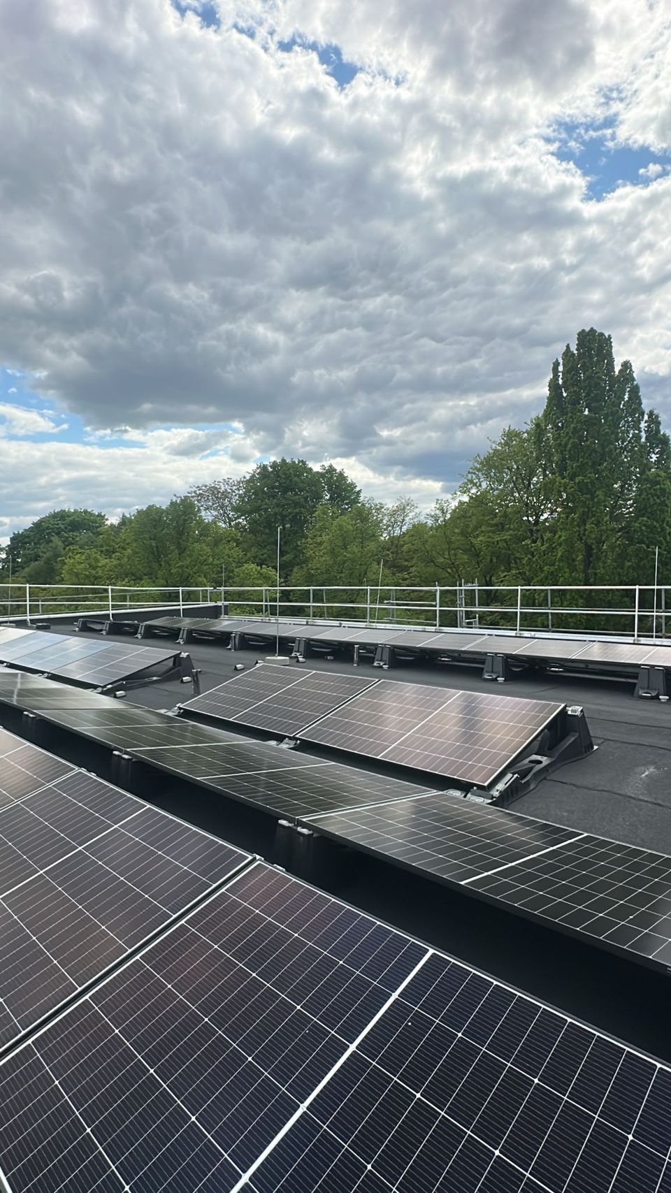 Aufgeständerte PV-Module in mehreren Reihen auf einem Flachdach mit Geländer