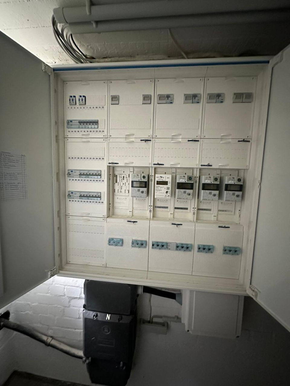 Geöffneter Zählerschrank mit mehreren elektronischen Zählern und einem Verteilerfeld, darunter der Hausanschlusskasten